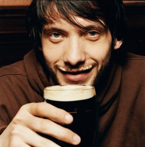 Young Man Enjoying a Drink of Stout in a Pub