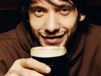 Young Man Enjoying a Drink of Stout in a Pub